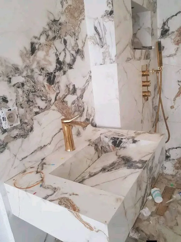 سطح مغسلة بمظهر رخام معرّق مع صنبور ذهبي